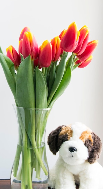 Close-up van tulpen in een vaas door een speelgoedhond op tafel