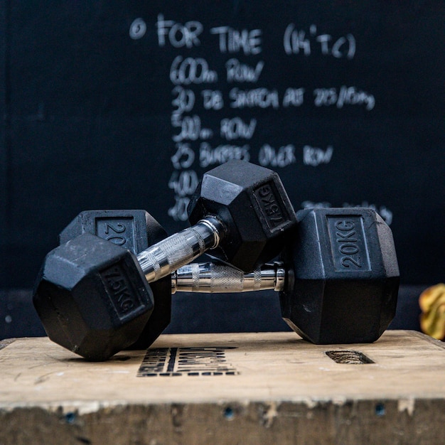 Close-up van twee halters op een houten kist voor bord in de sportschool Wod-training van de dag