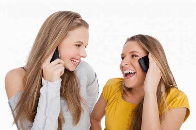 Close-up van twee jonge vrouwen die op de telefoon lachen