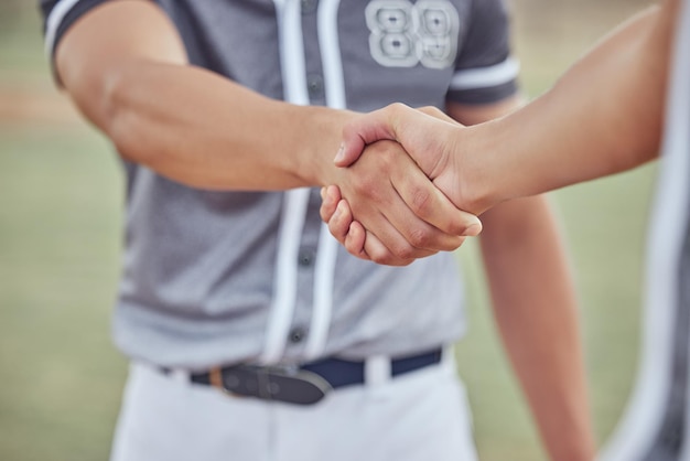 Close-up van twee sporters die handen schudden voor een wedstrijd Handen van honkbalspelers die elkaar feliciteren na het winnen van een wedstrijd Twee onbekende mannelijke concurrenten die elkaar succes wensen op het veld