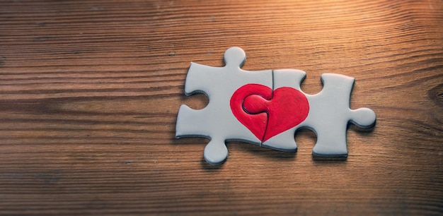 Foto close-up van twee stukjes van een puzzel met rood hart op houten achtergrond