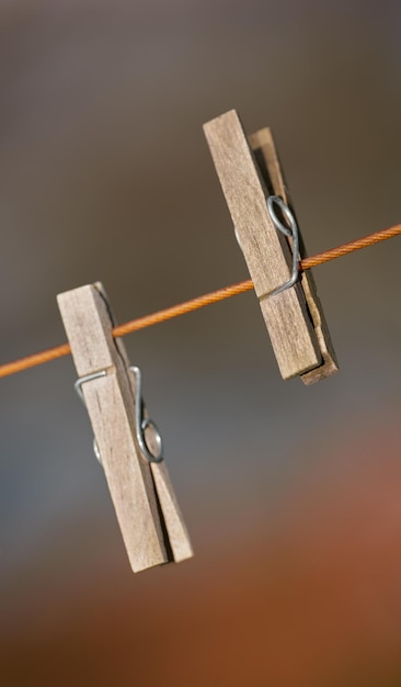 Foto close-up van twee wasknijpers op een waslijn buiten tegen een onscherpe achtergrond houten wasknijpers die worden gebruikt om schone was in de zon te knippen en op te hangen om te drogen als onderdeel van huishoudelijke en huishoudelijke taken