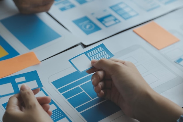 Close-up van ux-ontwikkelaar en ui-ontwerper brainstormen over wireframe-ontwerp van de mobiele app-interface op tafel met klant breif en kleurcode op modern kantoor Creatief bureau voor digitale ontwikkeling