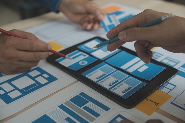 Close-up van ux-ontwikkelaar en ui-ontwerper brainstormen over wireframe-ontwerp van de mobiele app-interface op tafel met klant breif en kleurcode op modern kantoor Creatief bureau voor digitale ontwikkeling