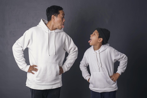 Close-up van vader en zoon poseren dom gezicht met witte hoodie voor kleding mock up geïsoleerd op