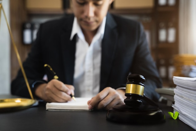 Close-up van veilinghamer op het bureau in advocatenkantoor en advocaat die document schrijft als rechtszaal