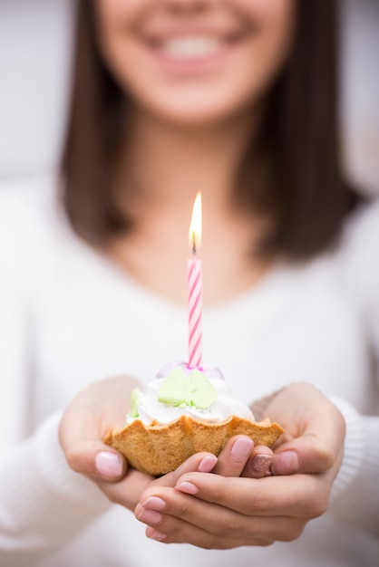 Close-up van verjaardagstaart. Jonge vrouw houdt cake.