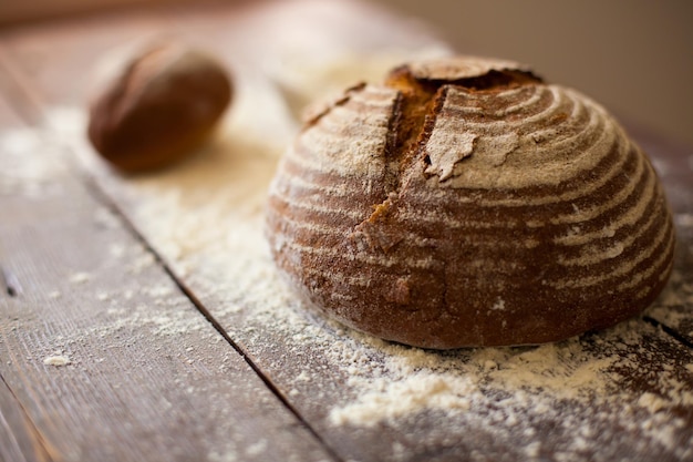 Close-up van vers bruin brood liggend op de houten tafel bestrooid met bloem