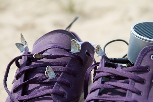 Foto close-up van verschillende mooie vlinders zittend op paarse sneakers in het strand