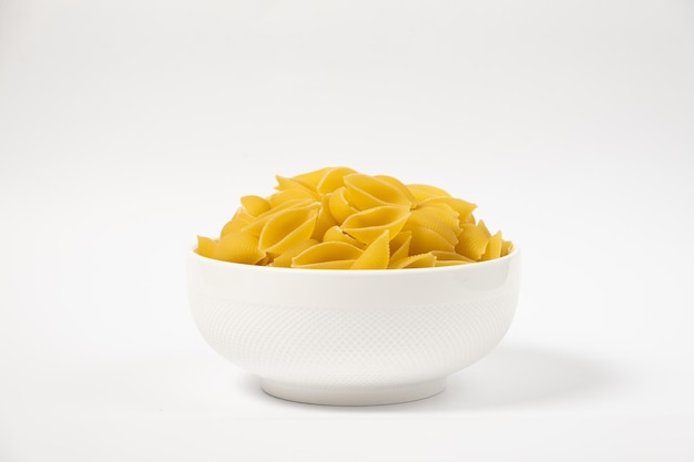 Close up van verschillende soorten droge pasta in een bord op witte achtergrond