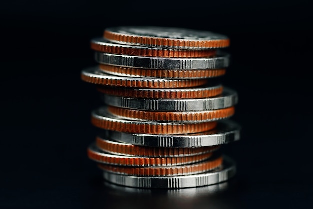 Close-up van verschillende soorten munten gestapeld op een zwarte achtergrond en geld besparen voor zaken of financiën