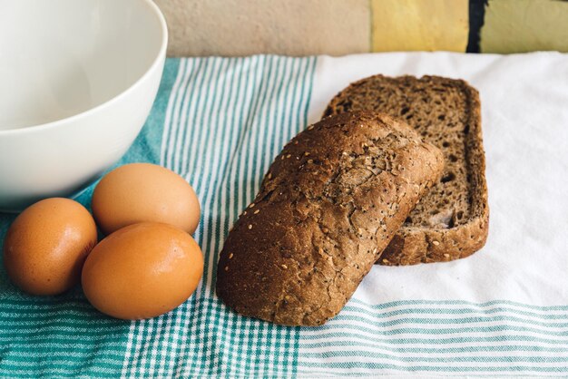 Foto close-up van verse eieren met bruin brood op tafeldoek aan tafel