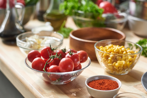 Close-up van verse groenten in kom op tafel met andere ingrediënten die voor het koken voorbereiden