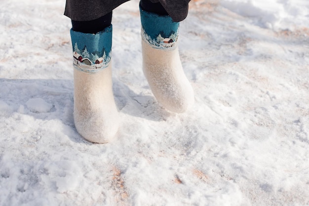 Close-up van vilten laarzen Man in witte vilten laarzen met orgelpatroon erop staat in de winter op pure sneeuw die viel na een zware sneeuwstorm