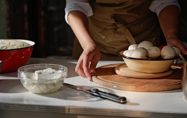 Close-up van voedselingrediënten op een witte tafel tegen een vrouwelijke huisvrouw in een schort van een chef-kok op een rustieke keukenachtergrond