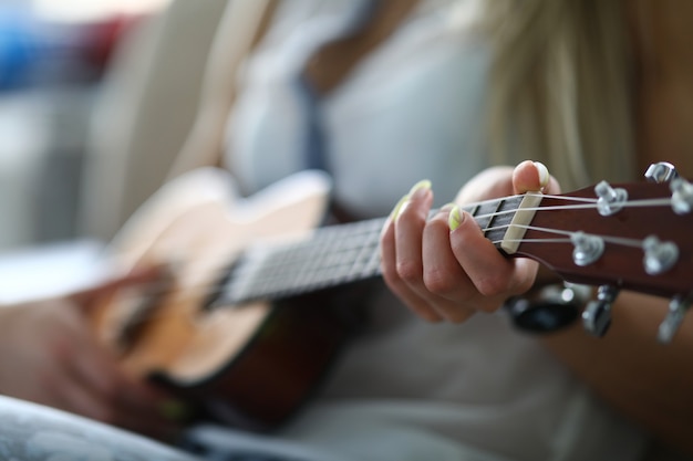 Close-up van volwassen persoon die akoestische gitaar houdt en melodie speelt. Vrouwelijke hand die op koord wordt geplaatst. Vrije tijd en vrije tijd. Getalenteerde vrouw. Muziek en hobby concept