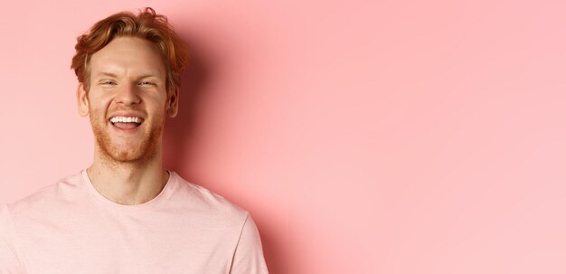 Foto close-up van vrolijke jonge man met slordig rood haar en baard lachend en glimlachend met witte tanden