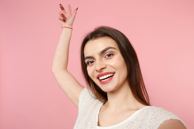 Close up van vrolijke jonge vrouw in casual lichte kleding poseren geïsoleerd op pastel roze muur achtergrond studio portret. Mensen levensstijl concept. Bespotten kopie ruimte. Selfie geschoten op mobiele telefoon doen.