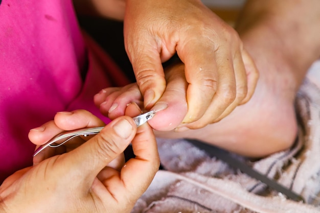 Foto close-up van vrouw die handen vasthoudt en teennagels snijdt en schoonheid vergroot