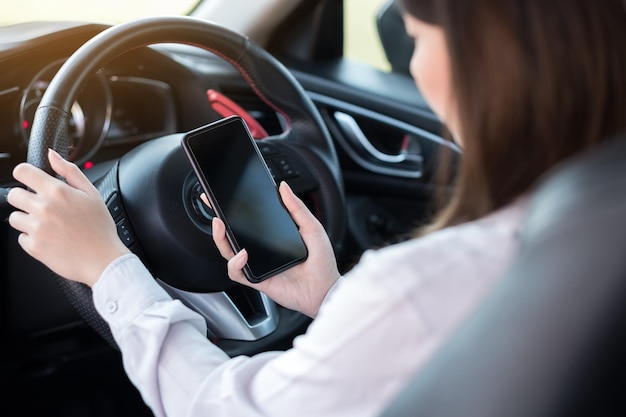 Close-up van vrouw die mobiele telefoon gebruikt in de auto