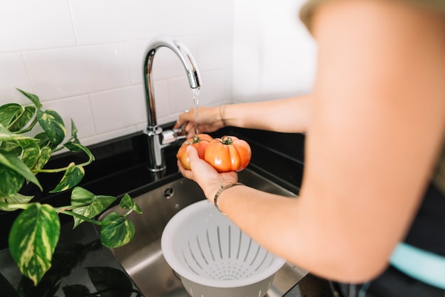 Foto close-up van vrouw die verse tomaten in gootsteen wast