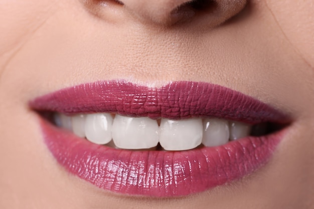 Close-up van vrouw glimlach met bordeauxrode lippen geschilderd met lippenstift. professioneel make-upconcept