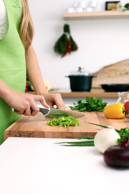 Close up van vrouw handen koken in de keuken. Huisvrouw die verse salade snijdt. Vegetarisch en gezond kookconcept.