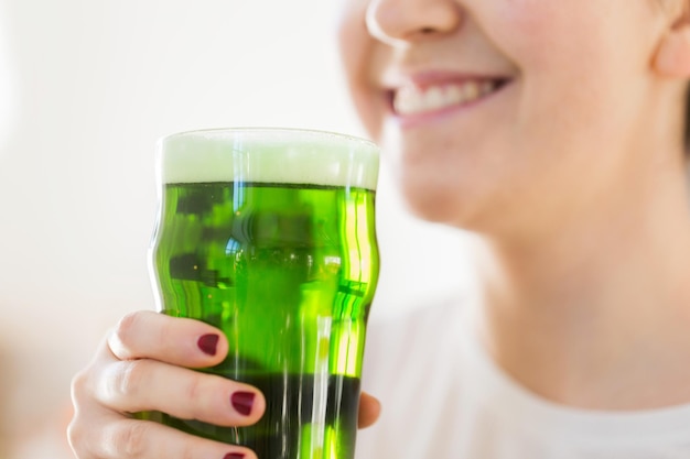 Close-up van vrouw met groen bier in glas