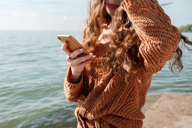 Close-up van vrouw met haar telefoon op een strand