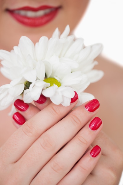Close-up van vrouw met rode lippen en rode geschilderde nagels die bloemen houden