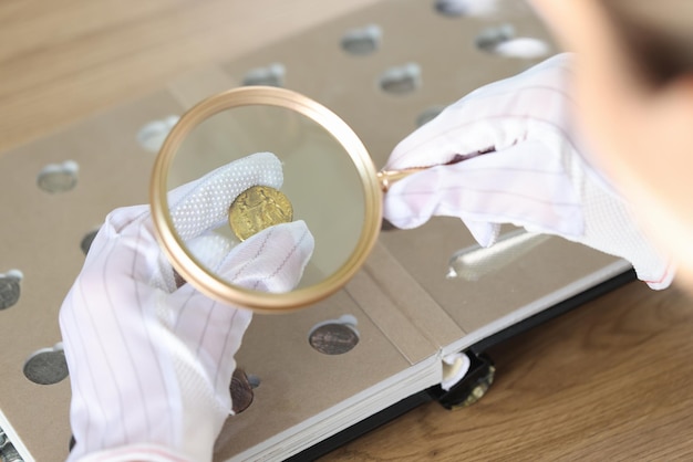 Close-up van vrouw numismaticus onderzoekt muntstuk met vergrootglas vrouw kijkt naar munten door loep