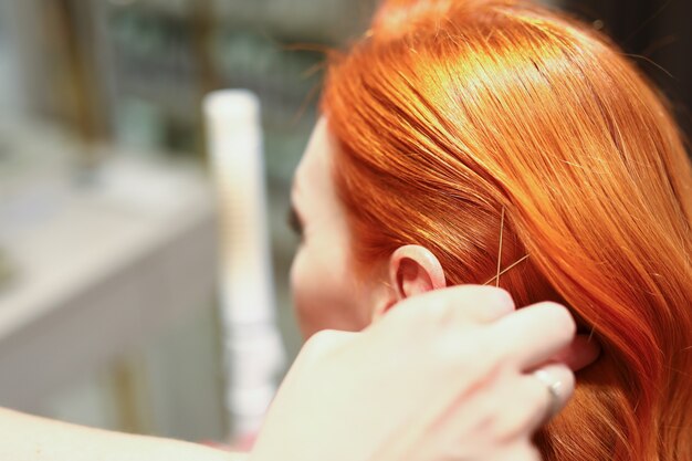 Close-up van vrouwelijk luxe rood haar met gouden accessoires professionele kapper creëren