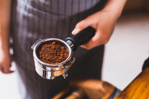 Foto close-up van vrouwelijke barista hand met espresso scoop met koffie poeder