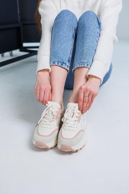 Close-up van vrouwelijke benen in jeans en casual sneakers Comfortabele casual damesschoenen Witte lederen damessneakers