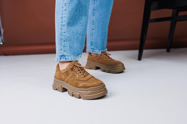 Close-up van vrouwelijke benen in spijkerbroek en bruine casual suède sneakers Dames zomerschoenen