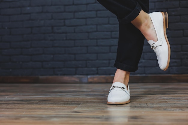 Close-up van vrouwelijke benen in zwarte broek en leren beige mocassins Nieuwe lente-zomercollectie van leren damesschoenen 2022