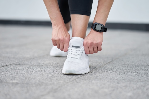 Close-up van vrouwelijke benen in zwarte sport legging in stijlvolle witte sneakers. Actieve slanke vrouw op een training. Klaar om te starten.