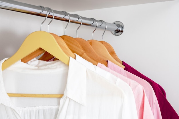 Close-up van vrouwelijke blouses die op hangers hangen van wit tot donkerroze gradiënt