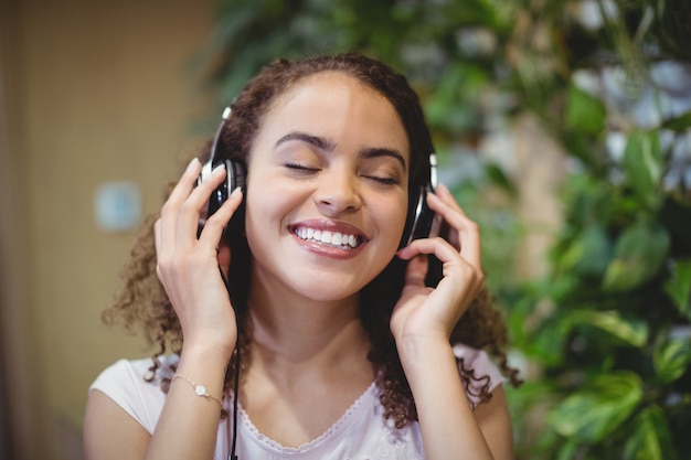 Close-up van vrouwelijke directeur het luisteren muziek op hoofdtelefoon