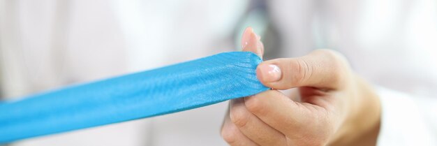 Close-up van vrouwelijke fysiotherapeut met blauwe medische tape in handen