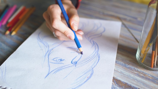 Foto close-up van vrouwelijke hand schilderen schets op papieren notitieblok met potloden vrouw kunstenaar op het werk