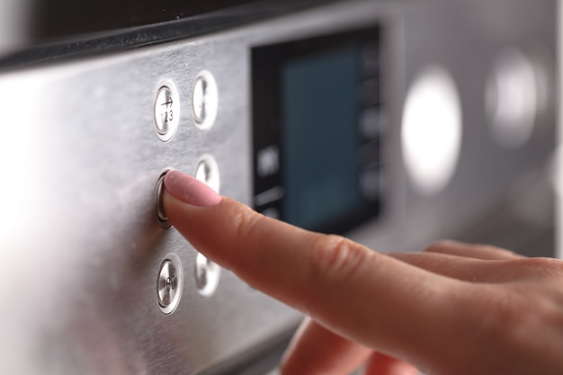 Close-up van vrouwelijke hand tijdens het gebruik van de magnetron in haar keuken