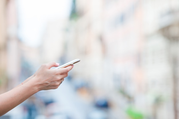 Close-up van vrouwelijke handen die cellphone in openlucht op de straat houden. Vrouw die mobiele smartphone gebruikt.