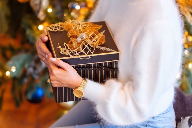 Close-up van vrouwelijke handen die een heden (giftdoos) houden. Kerstmis, Nieuwjaar