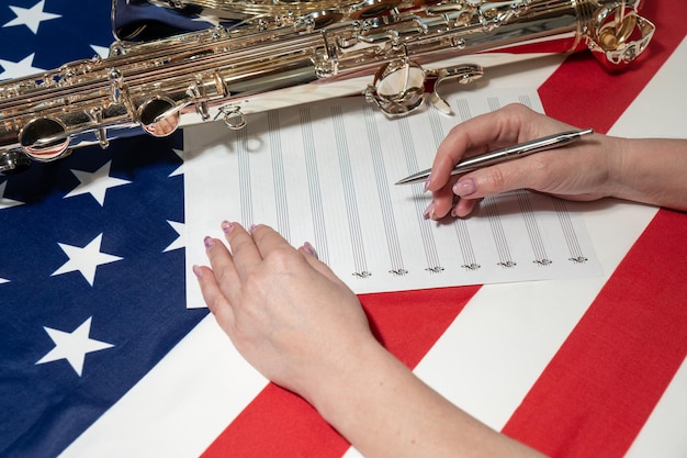 Close-up van vrouwelijke handen die muzieknoten schrijven tegen de achtergrond van de Amerikaanse vlag