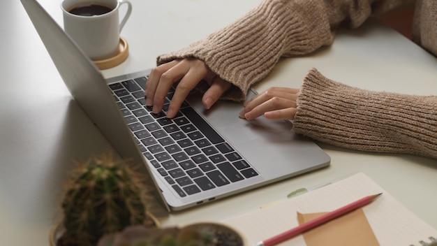 Close-up van vrouwelijke handen laptop toetsenbord op werktafel in kantoor aan huis kamer te typen