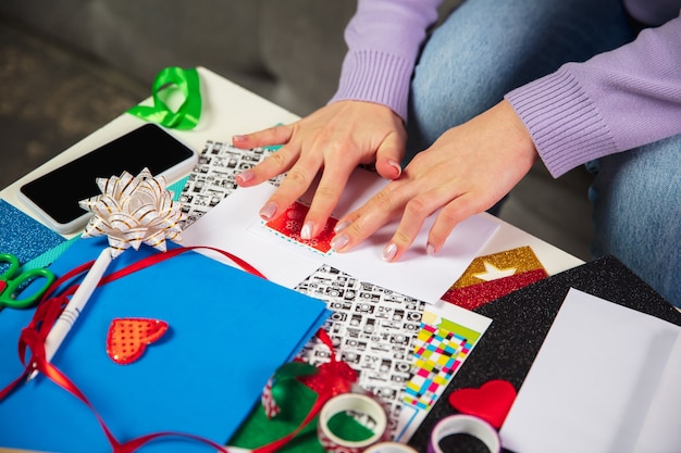 Close-up van vrouwelijke handen maken wenskaart voor Nieuwjaar en Kerstmis voor vrienden of familie