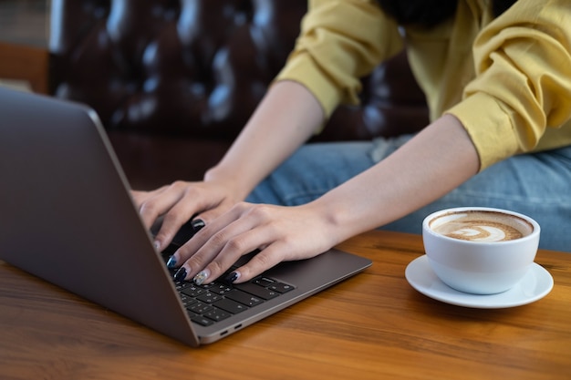 Foto close-up van vrouwelijke handen van een freelance bedrijf met behulp van laptopcomputer in café online werken