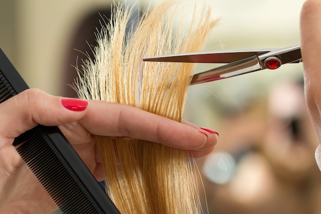 Close-up van vrouwelijke kapper handen haren tips knippen. Herstel van keratine, gezond haar, nieuwste haarmodetrends, veranderende kapselstijl, kortere gespleten punten, instrumentwinkelconcept