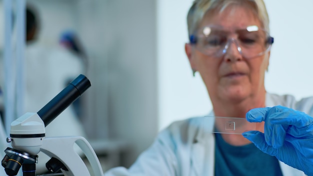 Foto close up van vrouwelijke laboratoriumingenieur die virusmonsters analyseert in een modern uitgerust laboratorium. senior arts die werkt met verschillende bacteriën, weefsel- en bloedonderzoeken, farmaceutisch onderzoek naar antibiotica